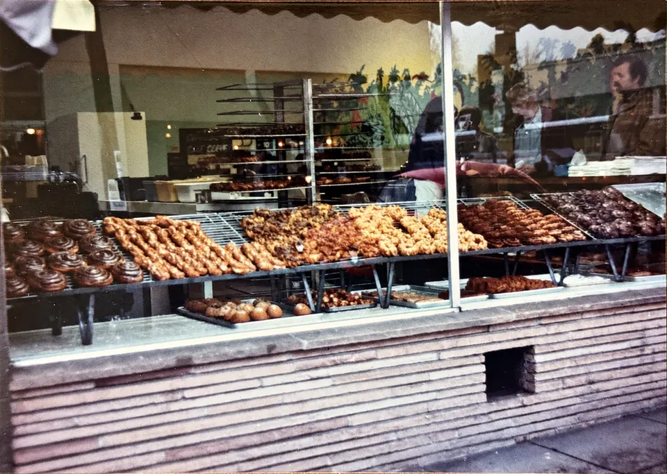 Colour photograph of the window of the family bakery on Ashby Avenue in Berkeley, with pastries on wire racks under a scalloped awning.