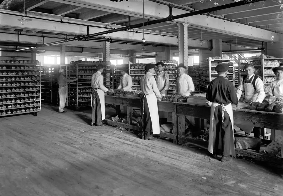 Black-and-white photograph of the wrapping room at the Gordon-Pagel Baking Co. in Detroit, 1914: workers in white aprons at long tables of loaves. Library of Congress.