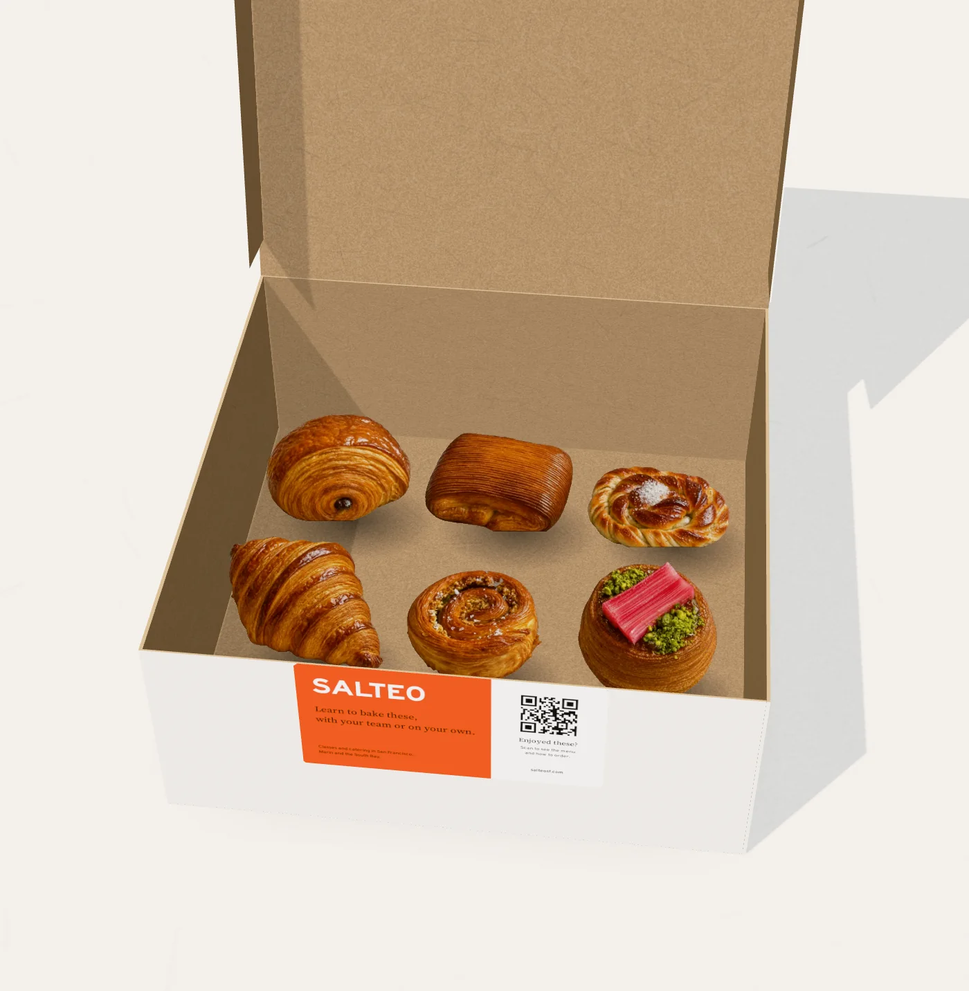 An open white Salteo box with six pastries in two rows: pain au chocolat, pain suisse and a cardamom bun at the back; a croissant, a kouign amann and a rhubarb and pistachio cup at the front; the orange Salteo label on the front
