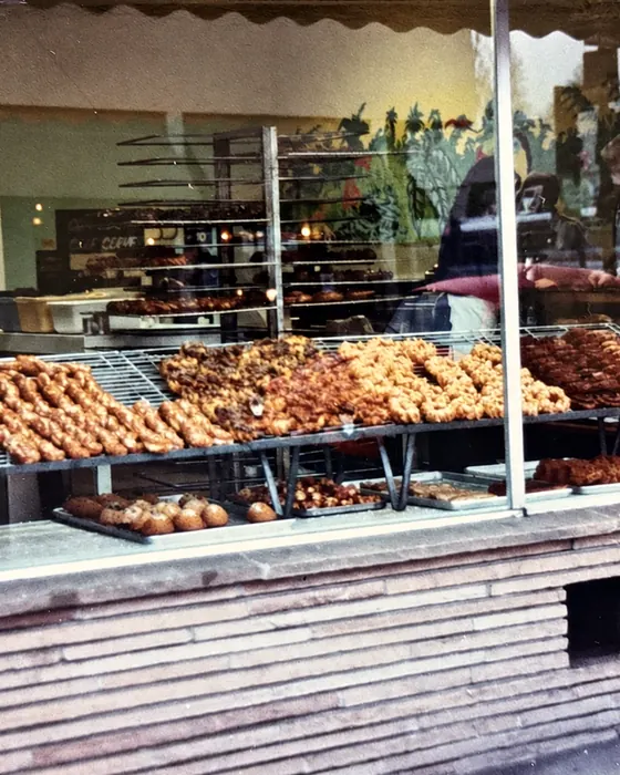 Colour photograph of the window of the family bakery on Ashby Avenue in Berkeley, with pastries on wire racks under a scalloped awning.